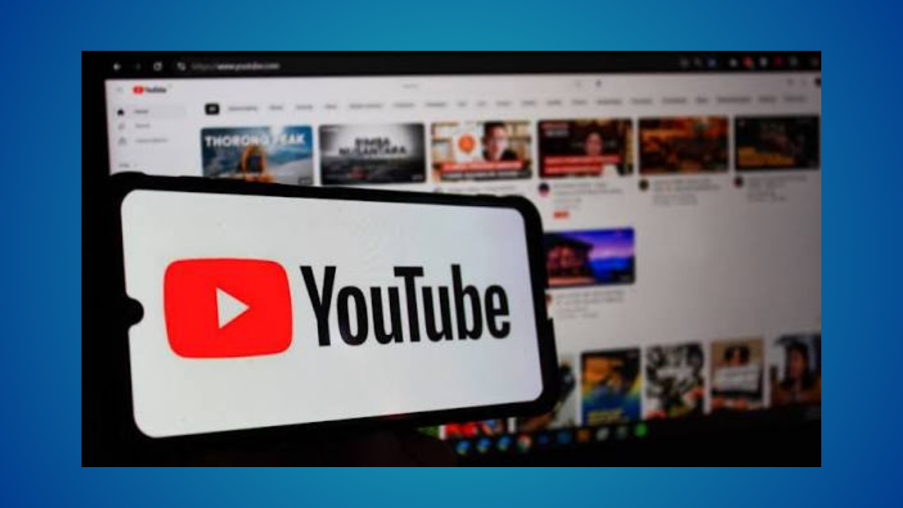 Smartphone in foreground shows the YouTube logo with a YouTube homepage visible in the blurred background on a monitor.