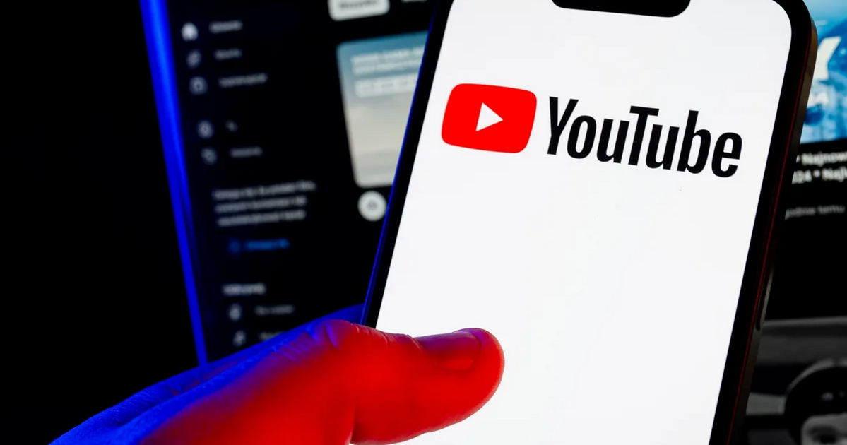 Hand holding a smartphone with the YouTube logo on the screen